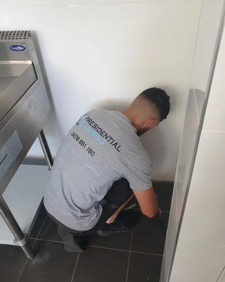 Presidential Plumbing Group plumber working on a commercial kitchen fitout