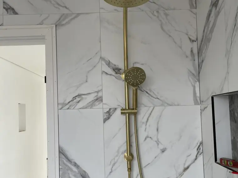 Marble-tiled shower with brushed brass rail shower installed